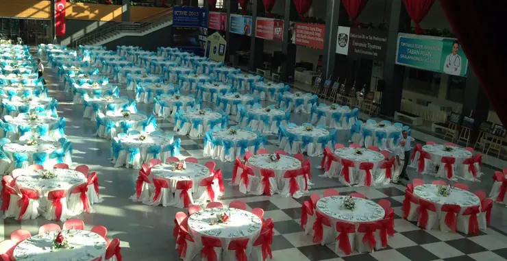 Yuvarlak masalar ve giydirilmiş sandalyelerle hazırlanan yemek salonu
