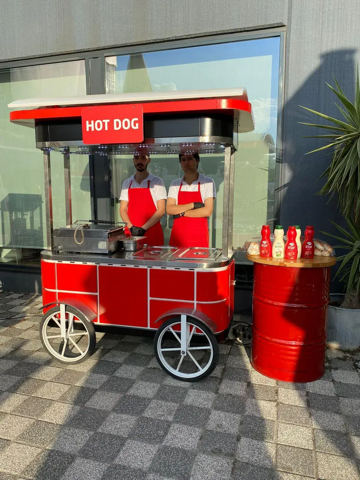 Kırmızı hot dog arabası ve görevlileri